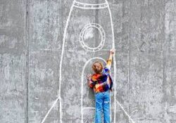 Little boy drawing a huge rocket on the wall.